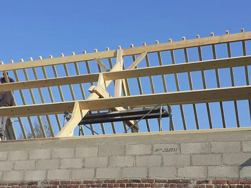 Charpente traditionnelle en bois avec assemblage de poutres apparentes réalisée par un charpentier.