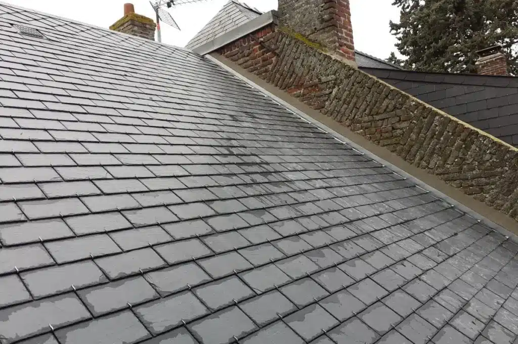 Vue en hauteur d’une toiture en tuiles en cours d’installation, montrant l'alignement soigné des éléments.