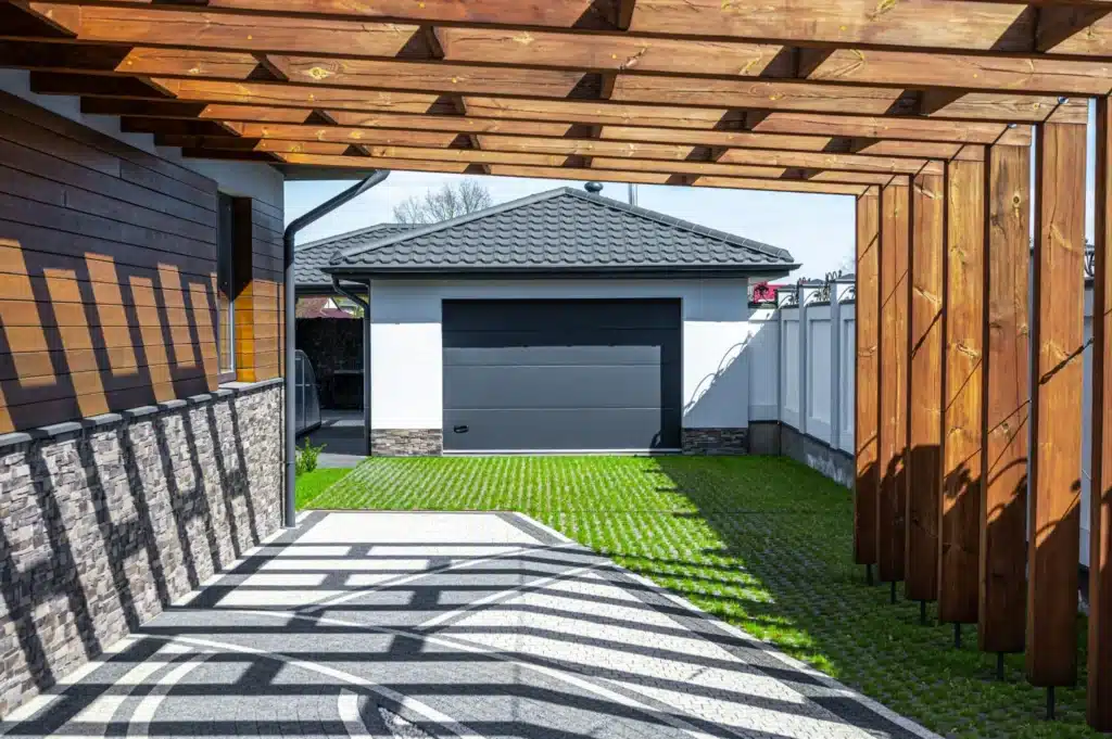 Carport en bois avec garage fermé et structure moderne, fabriqué pour s'adapter à l'esthétique de la maison.