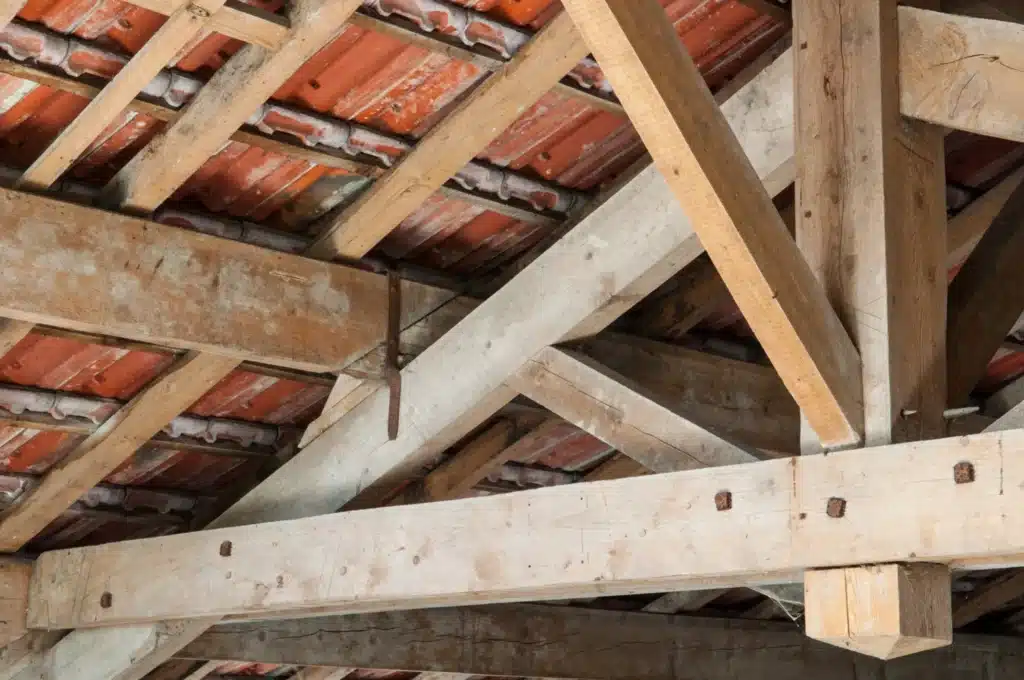 rénovation d'une charpente en bois ancienne montrant des poutres robustes et des éléments de fixation ​​