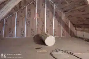 Isolation des combles avec rouleau de laine minérale installé dans une charpente en bois pour améliorer l'efficacité énergétique.