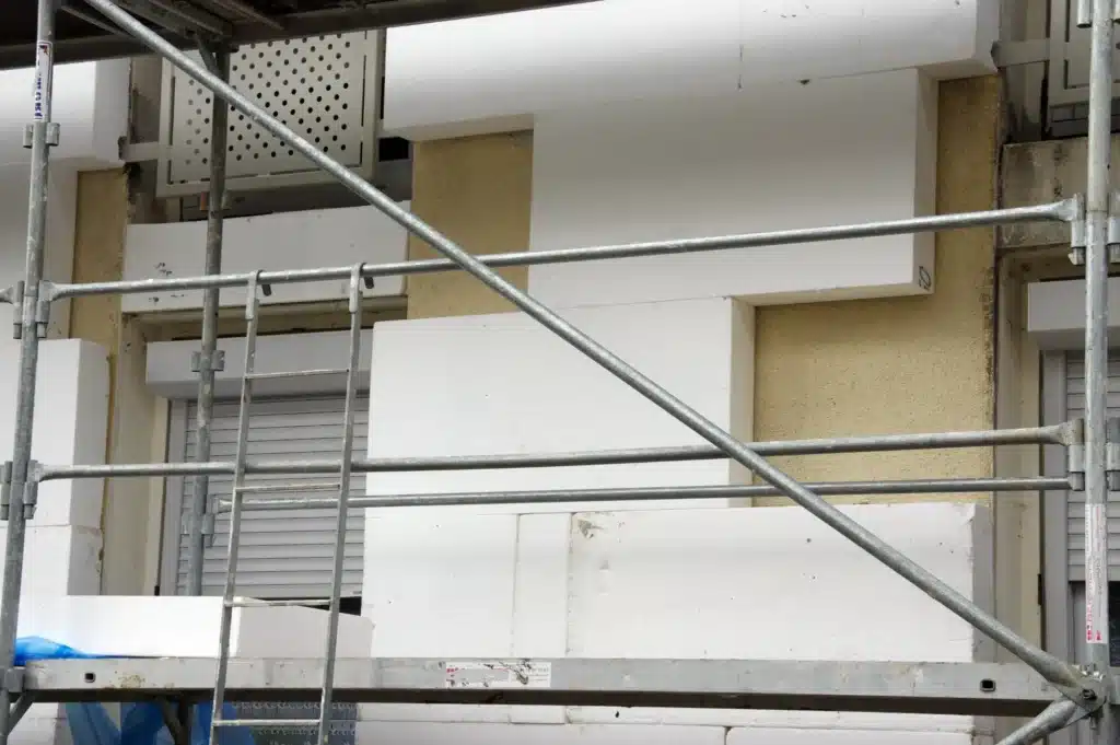 Application de panneaux de polystyrène pour l'isolation extérieure d'une façade de bâtiment en rénovation. ​​