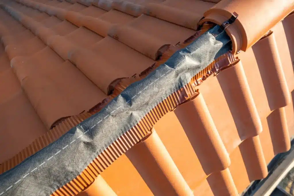 Détail de faîtage et étanchéité avec bande d’étanchéité sous les tuiles, pour une protection durable de la toiture.