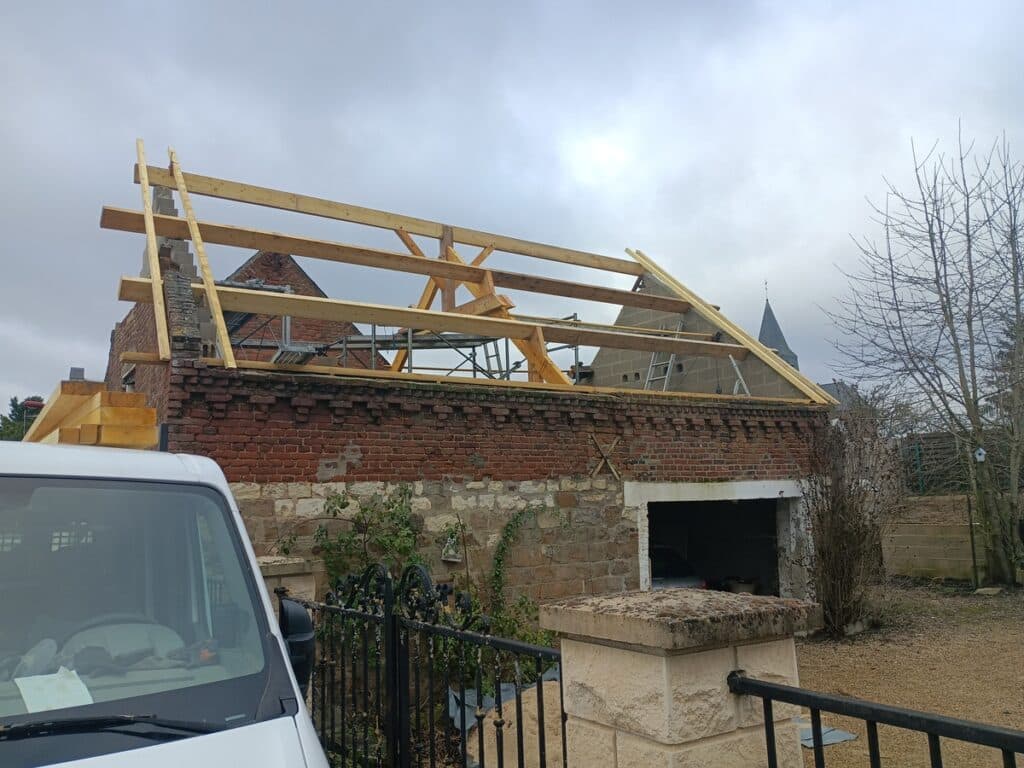 Installation de la charpente bois sur un ancien bâtiment en briques.